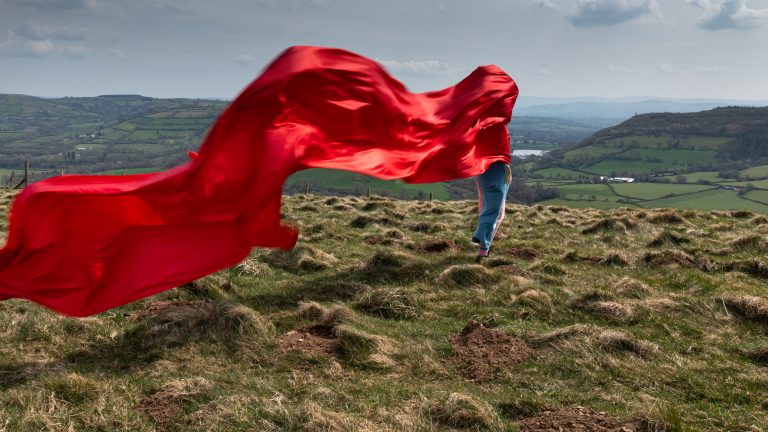 <h2>The Wind, Mountain and I, 2022</h2> <p><!-- wp:paragraph -->
<p>This live performance work was created whilst thinking through 18th C ideas of the sublime (Edmund Burke). Thoughts of transformative experience, scale, discomfort and awe prevailed. It also references Roland Hepburn’s ideas (1966) around the immersive appreciation of nature, walking in the landscape with the elements as a non-cognitive experience that emphasises sensory engagement. </p>
<!-- /wp:paragraph -->

<!-- wp:paragraph -->
<p>To make this work I walked three lengths of silk up on to the top of a mountain in southern Wales. I found an old tree branch and used this to connect the threads as I walked, trailing the silk in the wind behind me.</p>
<!-- /wp:paragraph -->

<!-- wp:paragraph -->
<p>As I walked it became apparent how little control I had over this process. The material, the wind and the landscape taking over, creating shapes, lines, routes across the landscape as I twisted and turned to navigate myself around these emerging patterns. </p>
<!-- /wp:paragraph --></p>