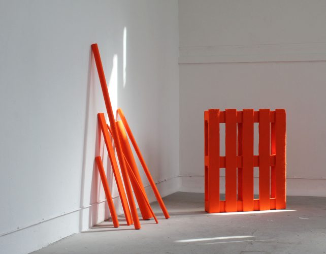 <h2>Happy Landing (regeneration via felting), 2012</h2> <p><!-- wp:paragraph -->
<p>Striking orange felt covers a pre-used wooden palette that is stripped of its functional purpose and stood upright in an open space. From a frontal distance the striking colour of the felted geometric lines creates a flat effect, as the three dimensional object loses all depth. Responding and reflecting the urban shadow lines that leak in to the exhibition space, the piece glows as if on fire with natural light. It transmits a soft orange tint to the surrounding walls, as if taking command of the space and leaking its colour all around.</p>
<!-- /wp:paragraph --></p>